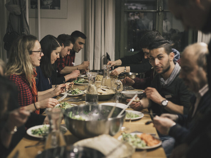Menschen sitzen am Tisch und essen gemeinsam