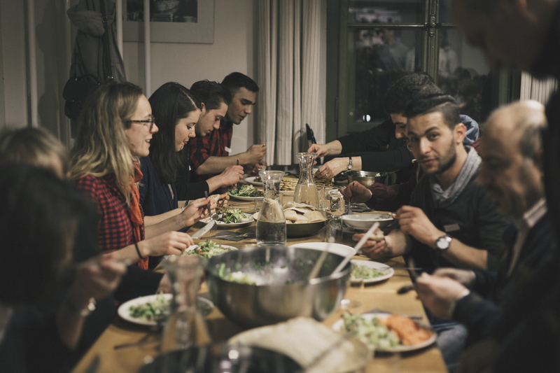 Menschen sitzen gemeinsam am Tisch und essen