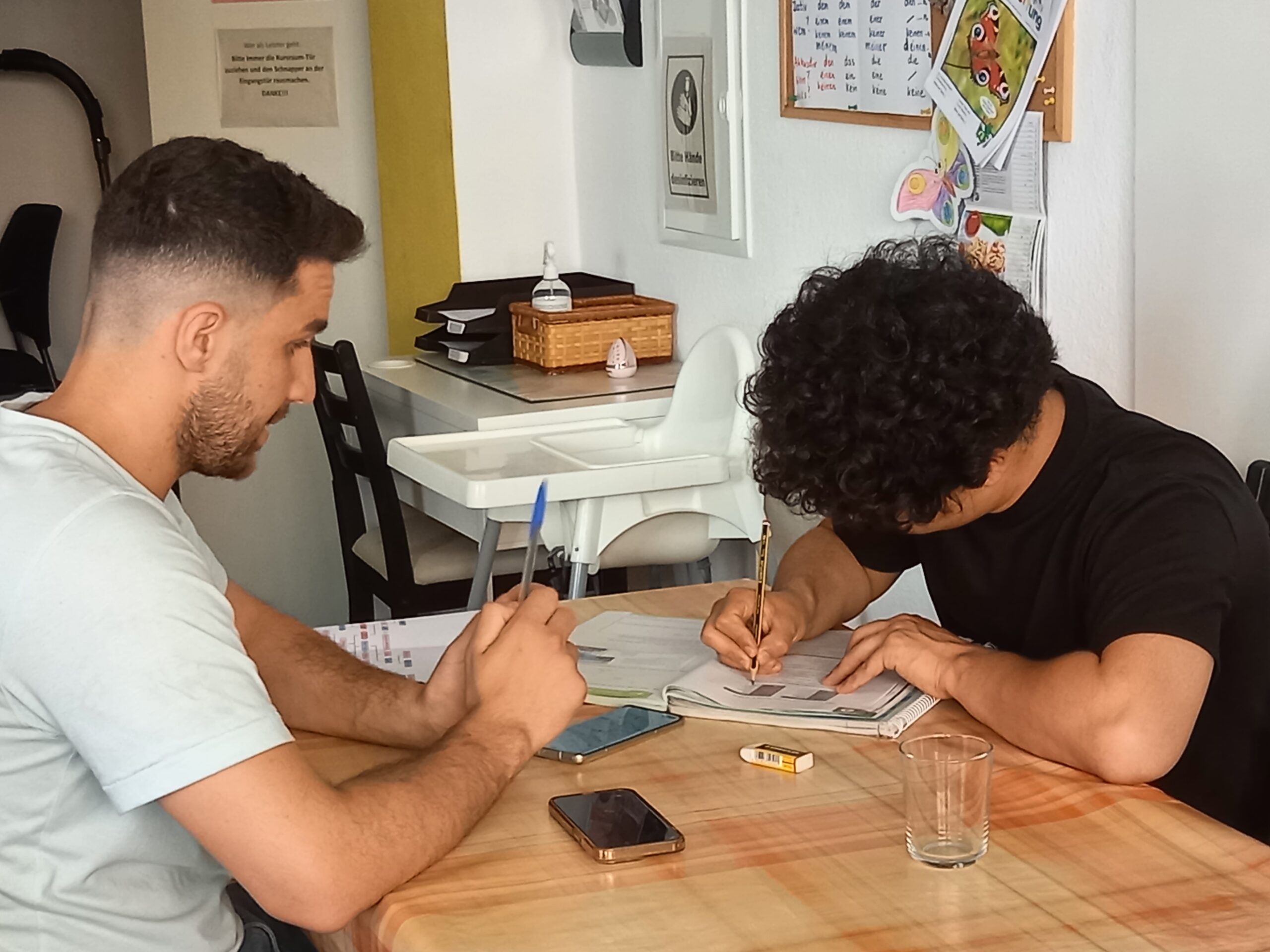 zwei junge Männer sitzen am Tisch und üben Deutsch