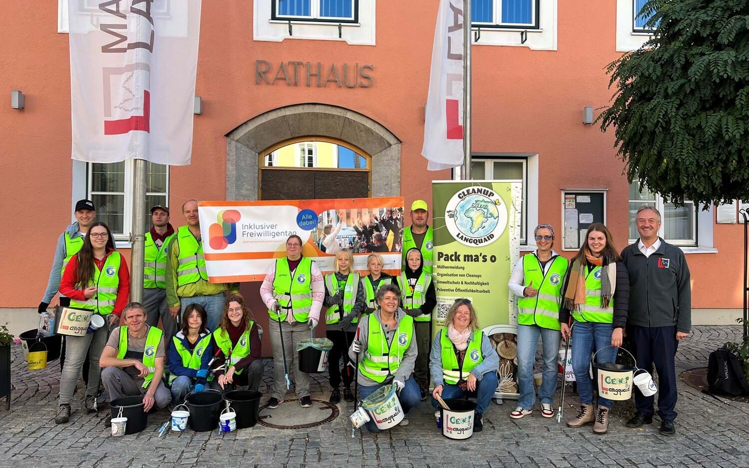 Eine Gruppe von Menschen, 3 Kinder, 6 Frauen und 7 Männer, posiert in neongelben Warnwesten vor dem Rathaus in Kehlheim. Sie haben Eimer in der Hand.