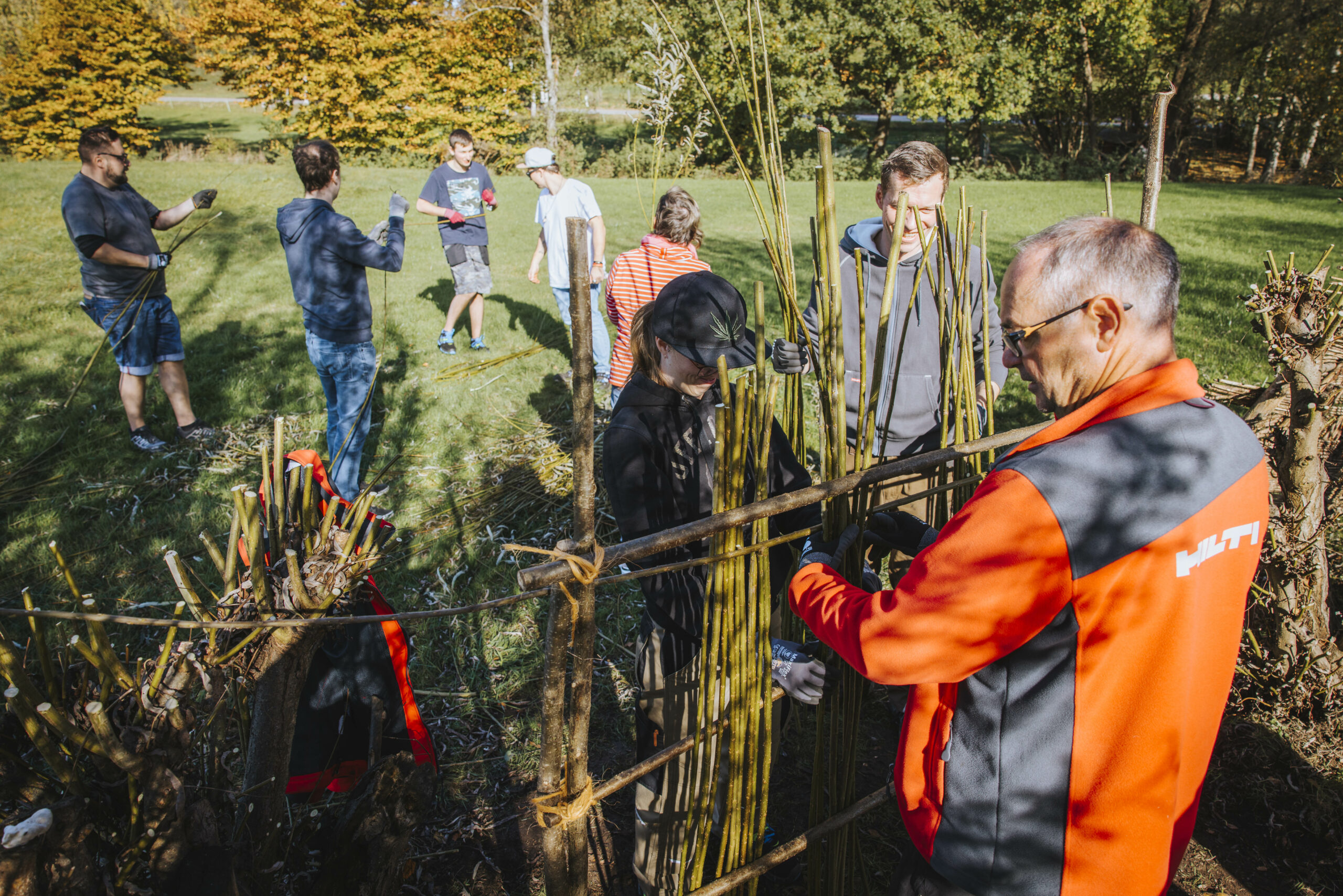 Ein Mitarbeiter von Hilti und einige junge Menschen bauen gemeinsam an einem Weidezaun